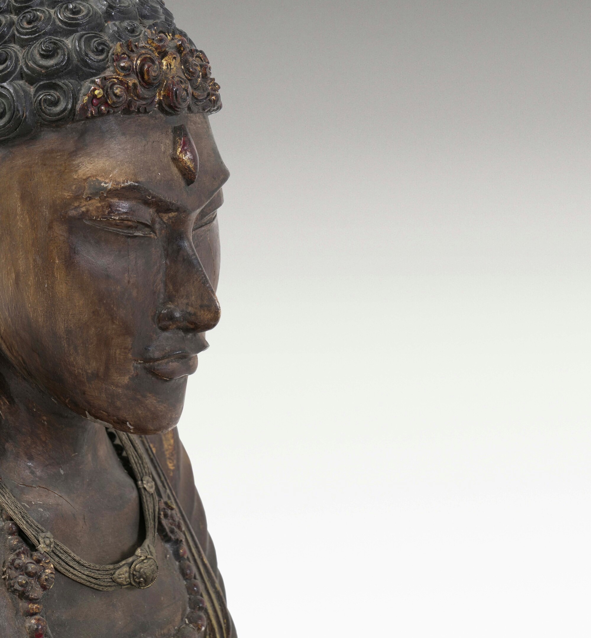 Figura di Buddha, legno con tracce di policromia e collane, Tibet, XX secolo