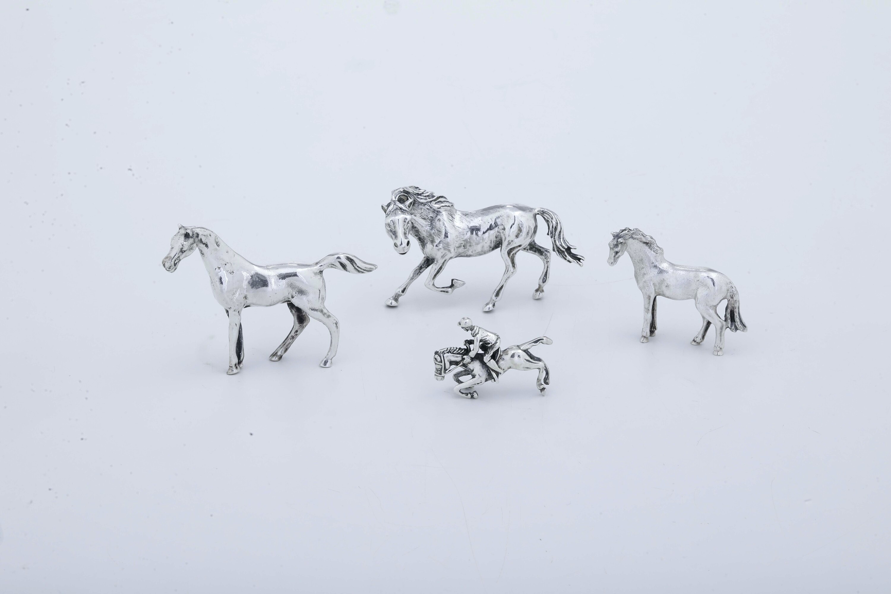 Manifattura italiana del XX secolo, Lotto di quattro figure equestri in argento fuso e sagomato