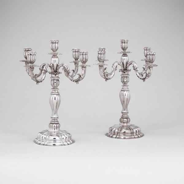 Coppia di grandi candelabri a cinque luci di gusto neobarocco. Argenteria artistica milanese, marchi con fascio littorio in uso dal 1935 al 1945. Argentiere Gianni Prosperini.