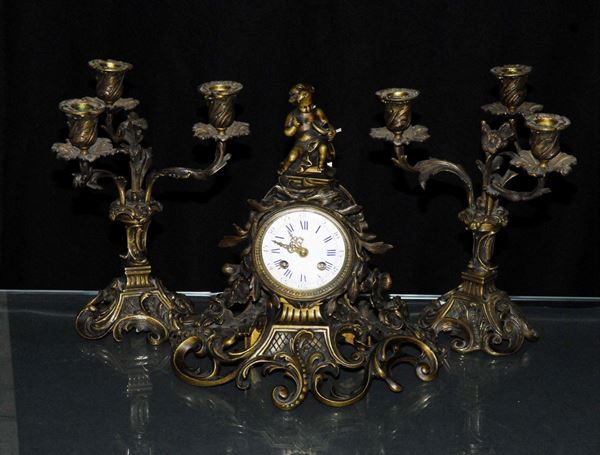 Trittico composto da orologio e due candelieri in bronzo