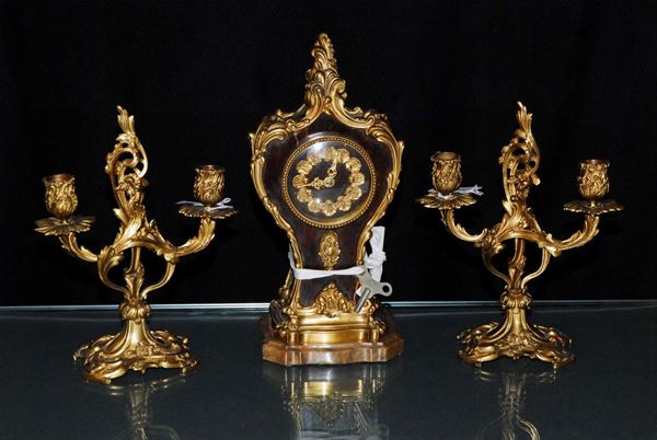 Trittico composto da orologio e due candelieri in legno e bronzo dorato