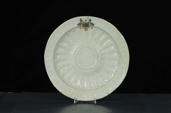 Piatto in maiolica bianca baccellata con stemma policromo, Italia XVII secolo
